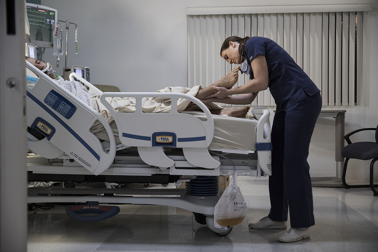 Patient laying in hospital bed while a clinician reviews their pressure injury